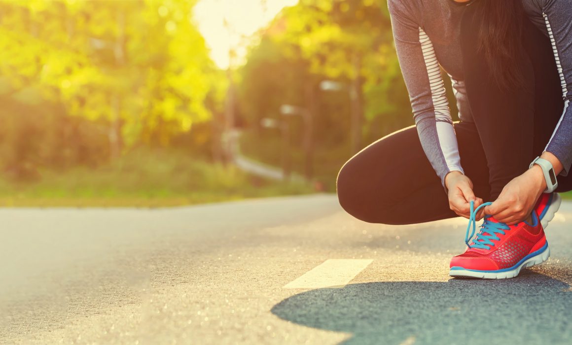 Female runner tying her shoes preparing for a run a jog outside